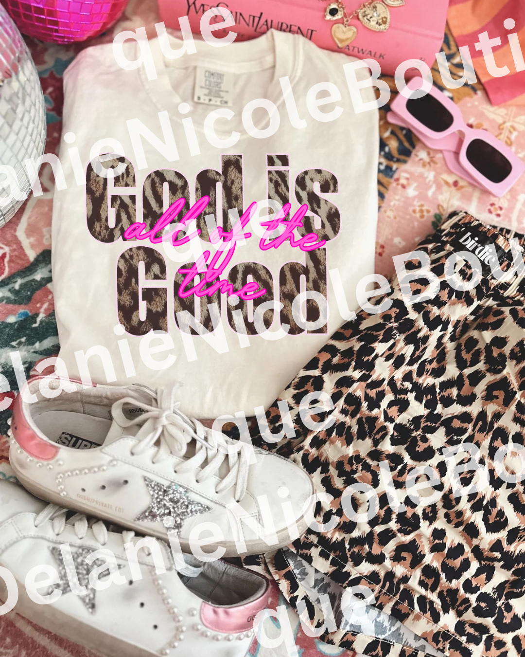 White t-shirt with text and leopard print pattern, paired with white sneakers on a colorful background. God is Good all the time Chettah print